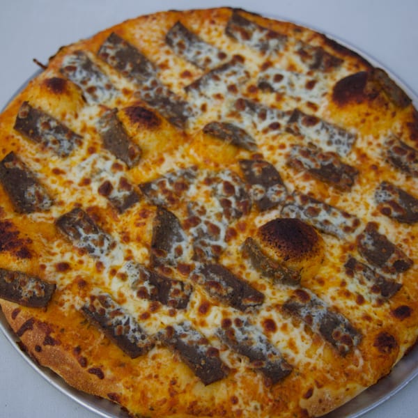 Moon Pizza's cheesy pizza with strips of meat, possibly steak or lamb, arranged in rows.
