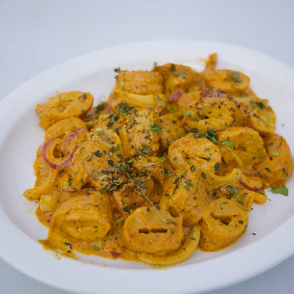 Moon Pizza's creamy pasta dish with red onions and herbs on a white plate.