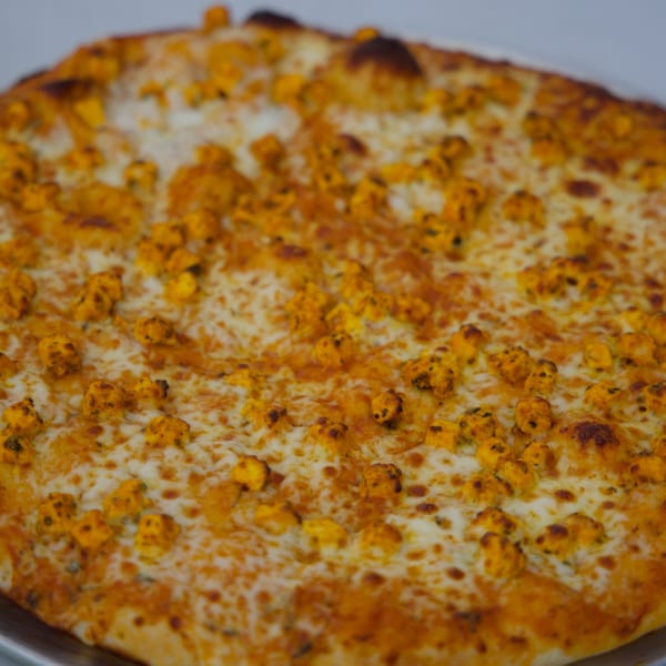 Close-up of a Moon Pizza with melted cheese and golden-brown paneer cubes.