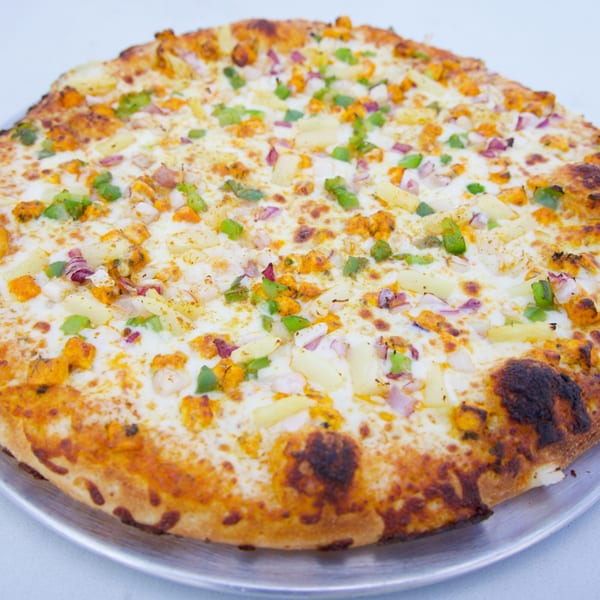 Moon Pizza's chicken, pineapple, red onion, and green pepper pizza on a metal tray.
